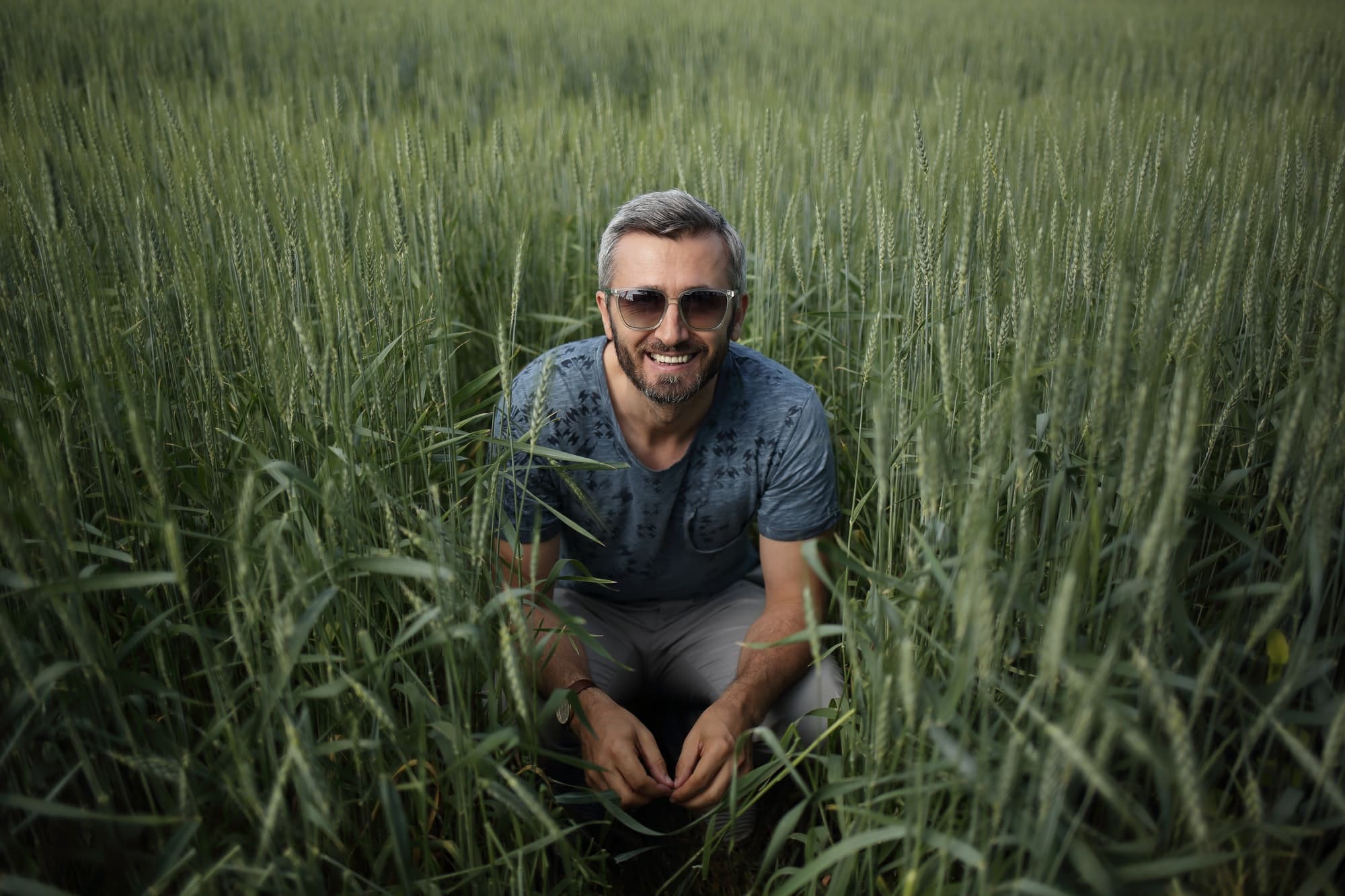 A man is crouching in the wheat field