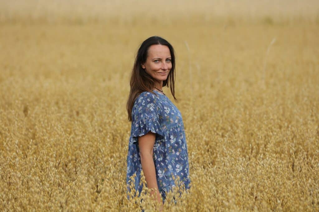 femme heureuse dans un champ regarde la caméra